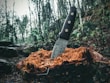 A hunter holding a forged hunting knife with a leather sheath in a forest setting