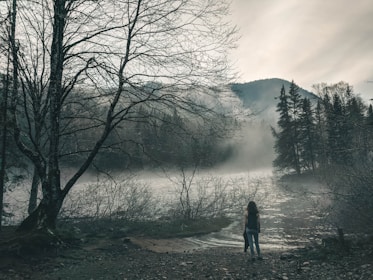 A shadowy figure with glowing eyes standing at the edge of a moonlit lake.