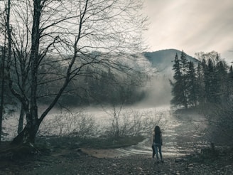 A shadowy figure with glowing eyes standing at the edge of a moonlit lake.