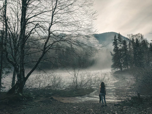 A focused man standing at the edge of a misty forest, symbolizing the threshold of transformation.