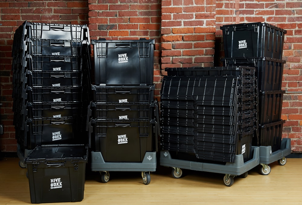 black plastic storage boxes beside brown brick wall