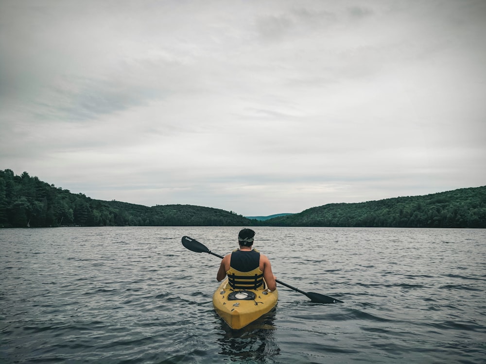 personne en kayak jaune sur plan d’eau pendant la journée