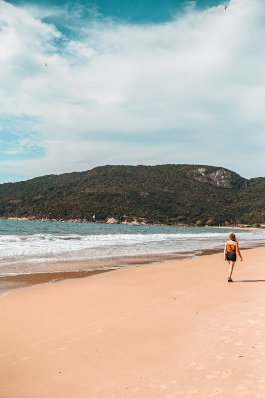 man in black shorts walking on beach during daytime in Florianópolis Brasil