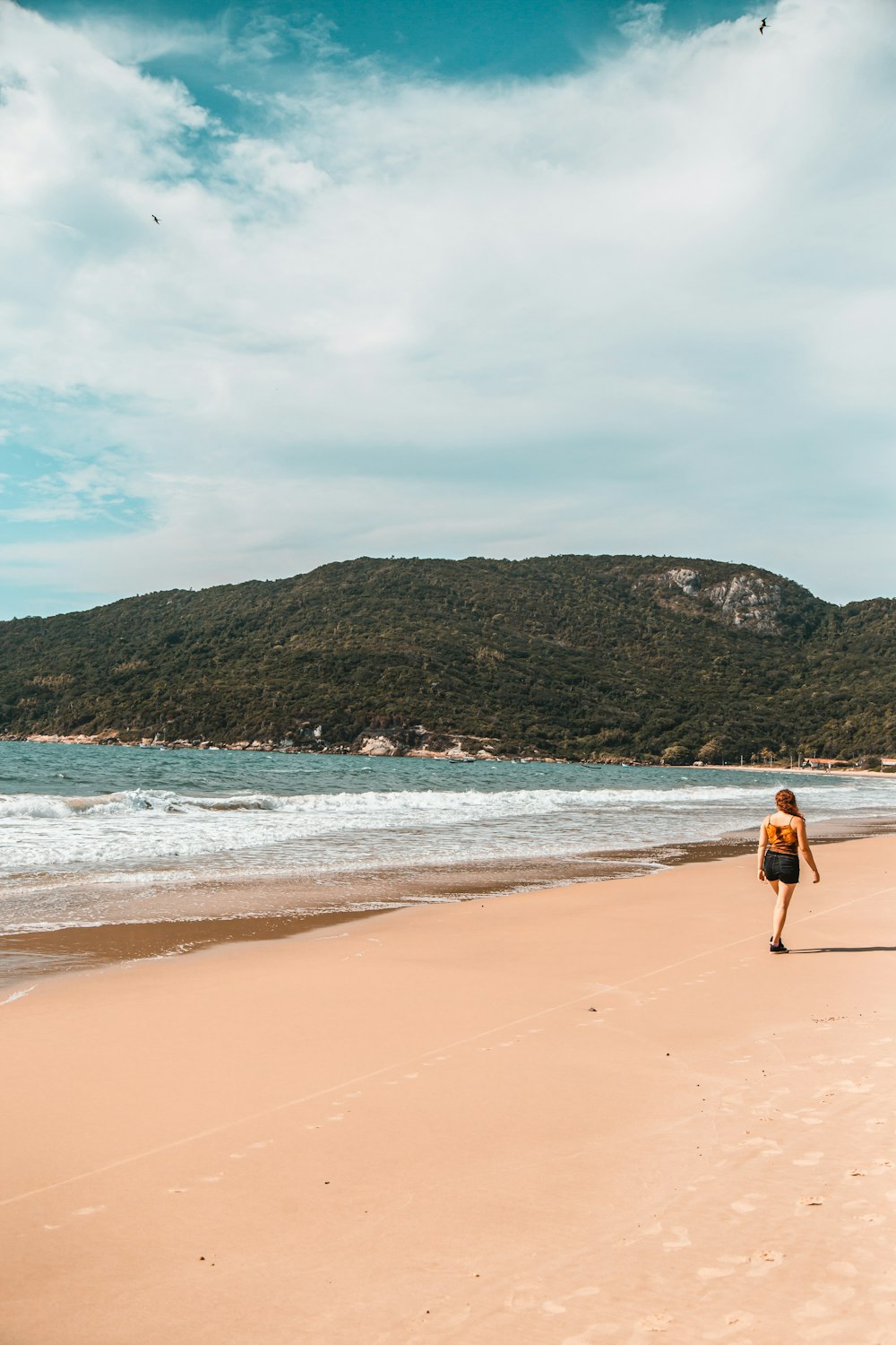 man in black shorts walking on beach during daytime