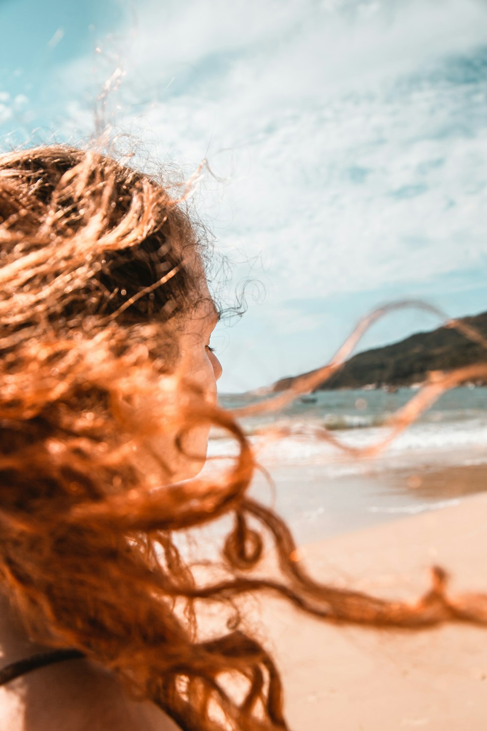 woman with brown hair on beach during daytime