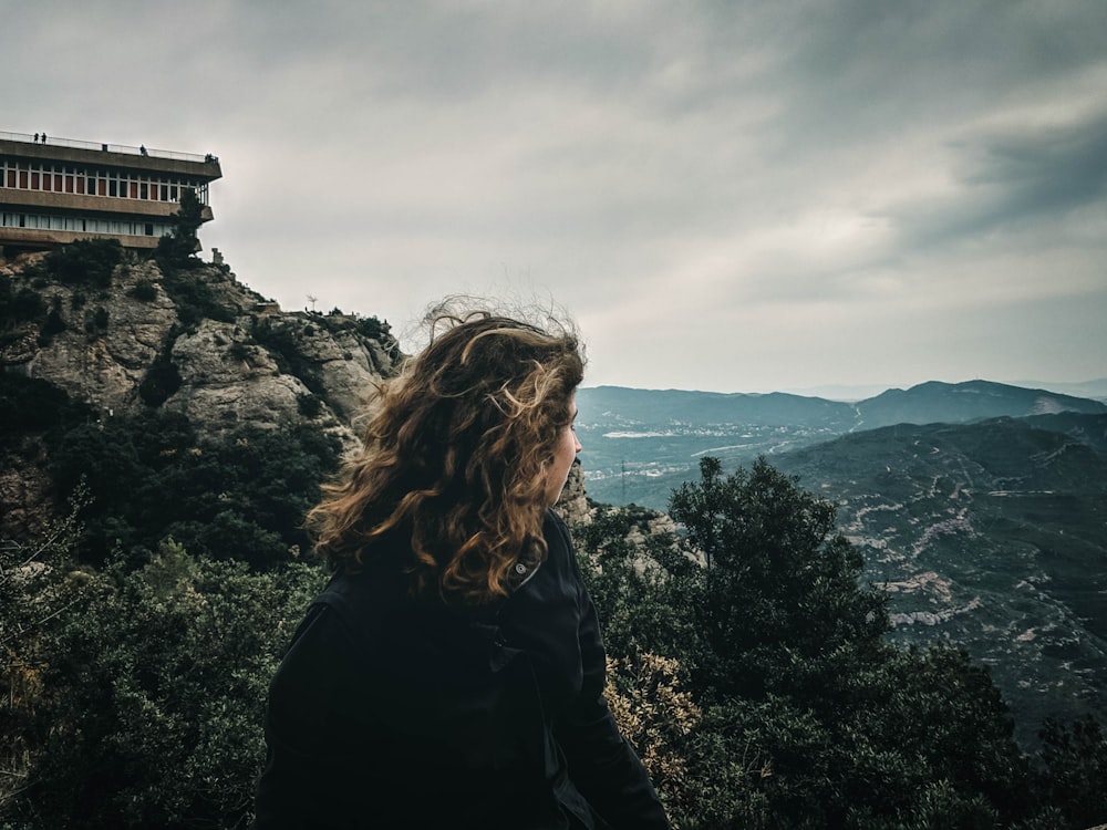 woman in black jacket standing on top of mountain during daytime