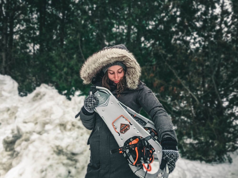 woman in black jacket holding white and red snow sled