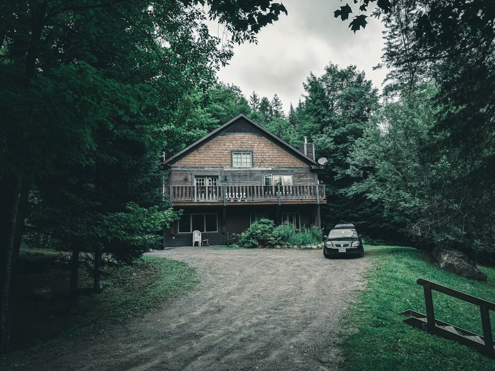 casa de madera marrón cerca de árboles verdes bajo nubes blancas durante el día
