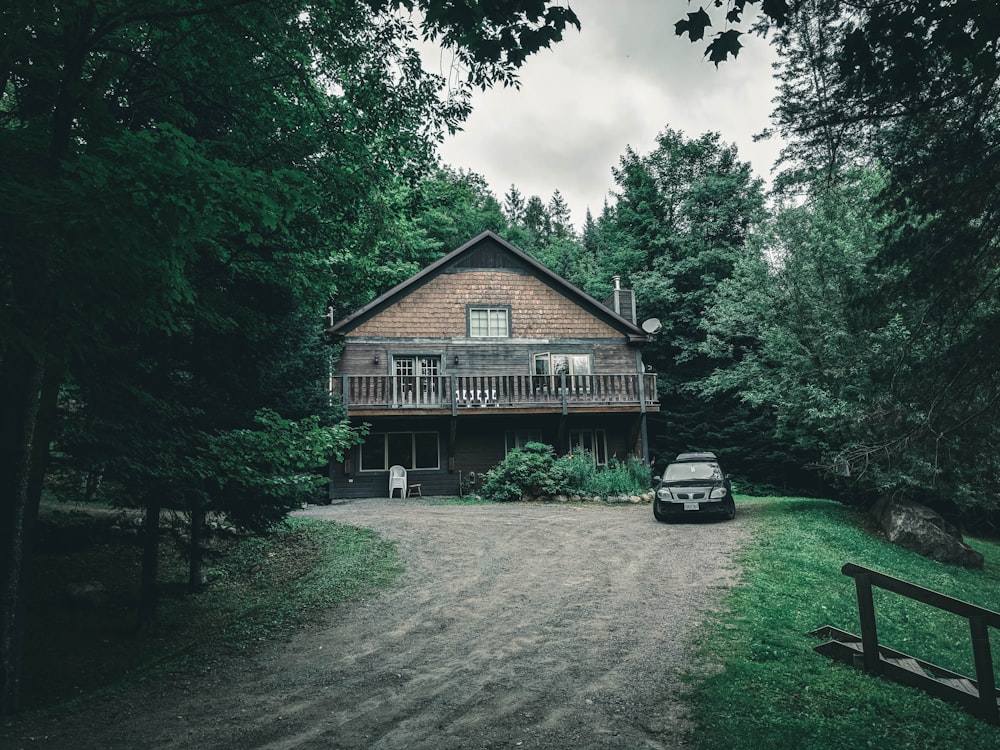 maison en bois brun près des arbres verts sous les nuages blancs pendant la journée