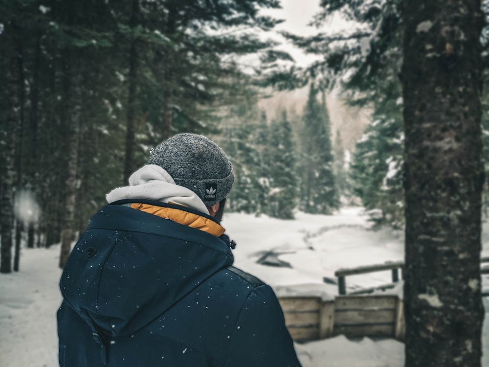 person in black jacket and gray knit cap standing on snow covered ground during daytime