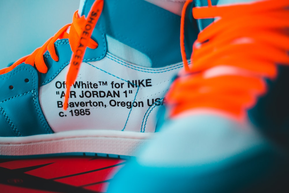 a close up of a pair of sneakers with orange laces