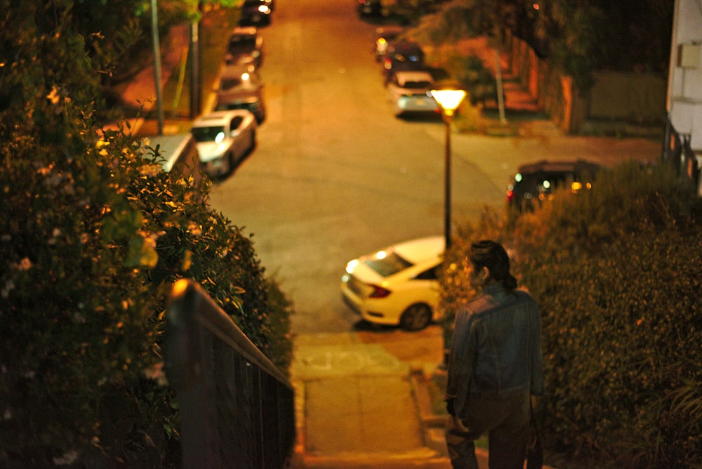 homme en veste noire debout sur le trottoir pendant la nuit