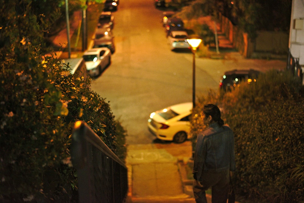 man in black jacket standing on sidewalk during night time