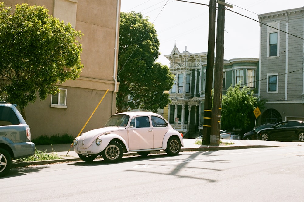 white coupe parked beside gray concrete building during daytime