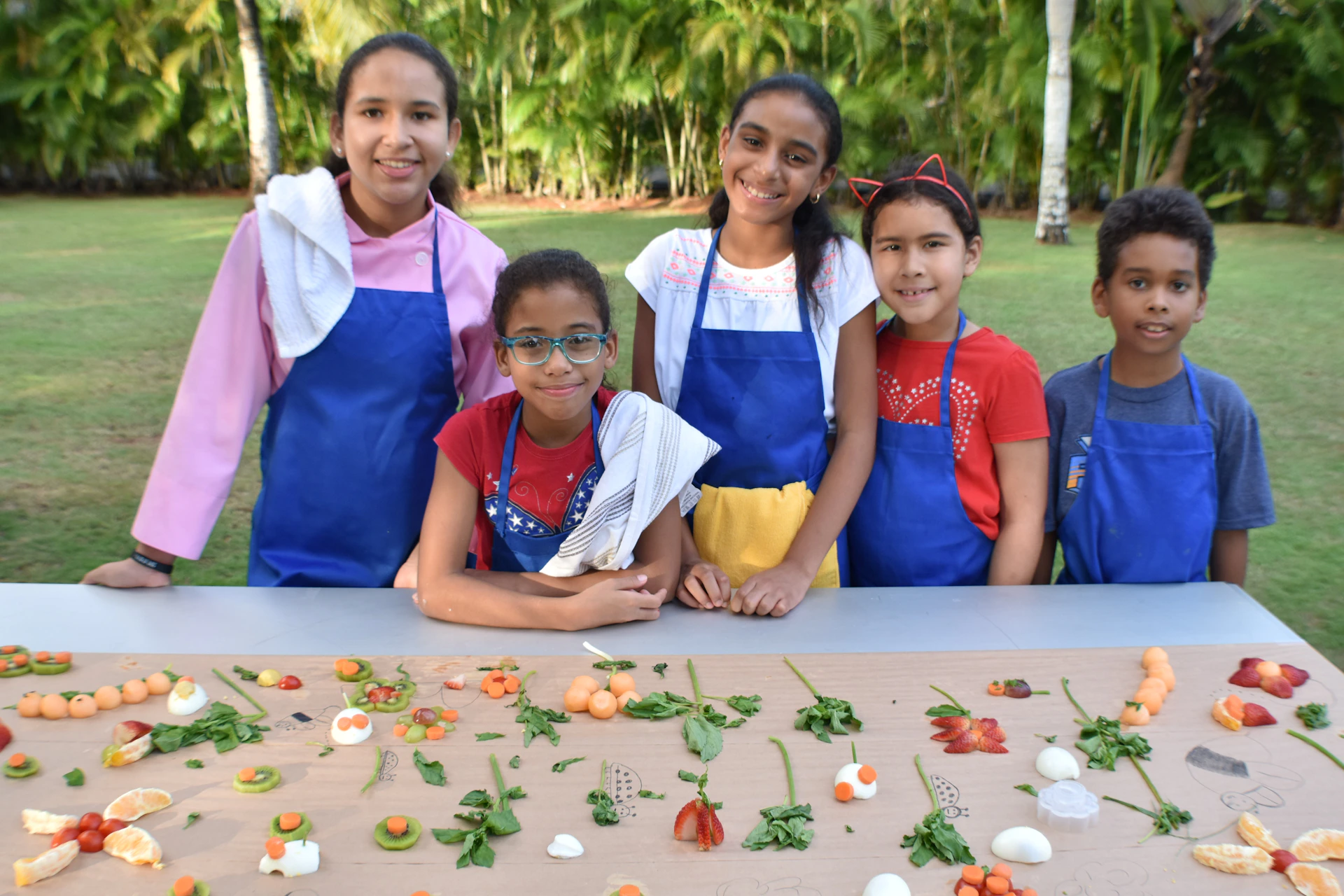 A lively group of children, including several Black kids, joyfully participating in a colorful cooking class at Brightsteps Academy, with aprons and chef hats.