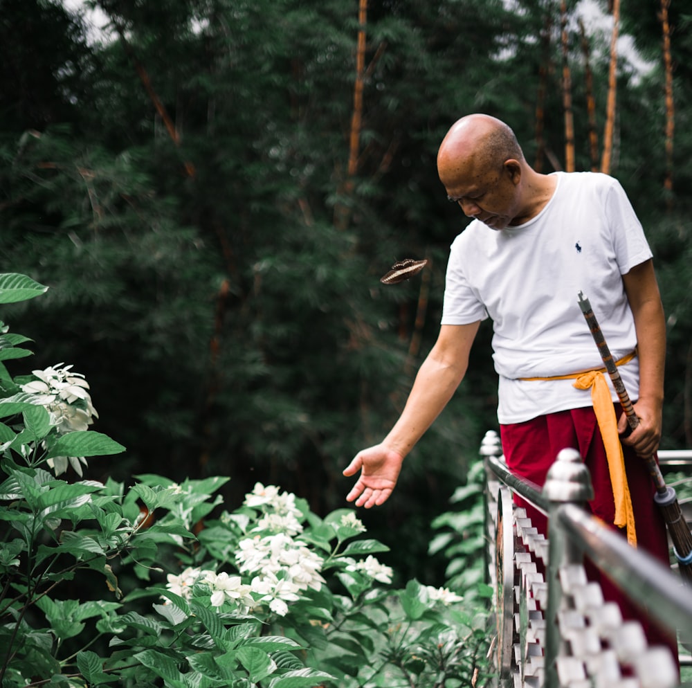 man in white crew neck t-shirt and brown shorts standing on red metal railings during