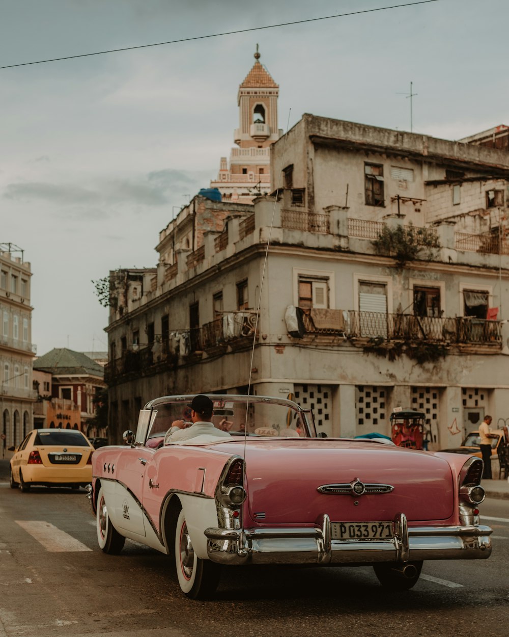 red and white vintage car on road near building during daytime