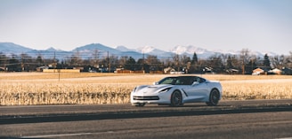 Sleek white transport truck carrying a premium German sports car through scenic route.