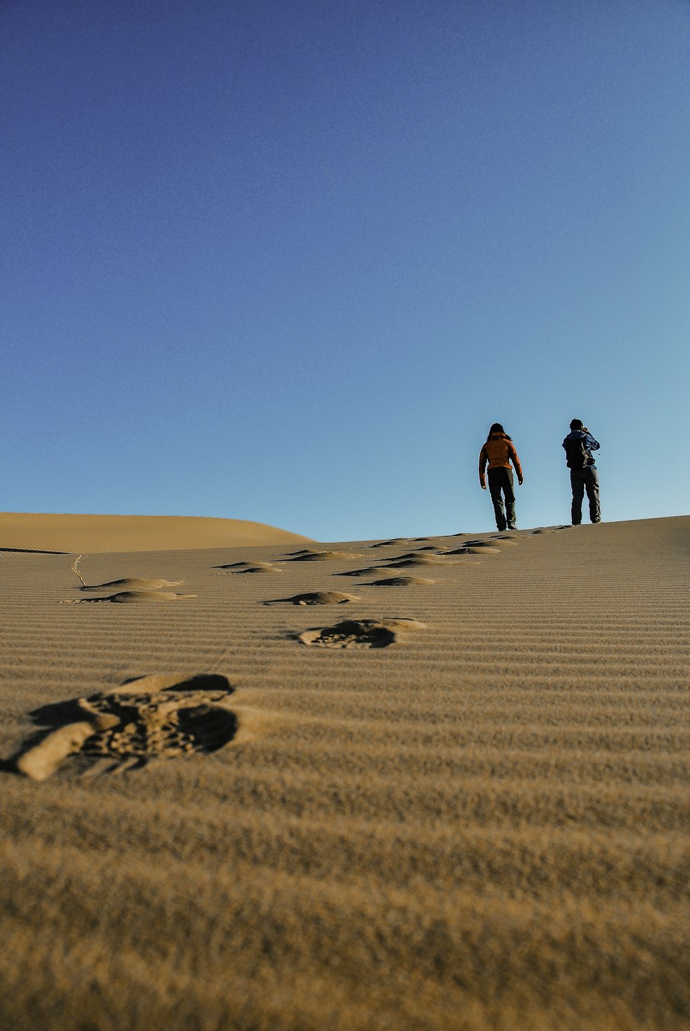 man in red jacket walking on sand during daytime