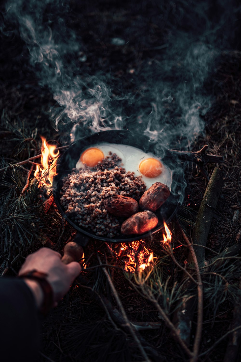 person holding a black cooking pot with fire