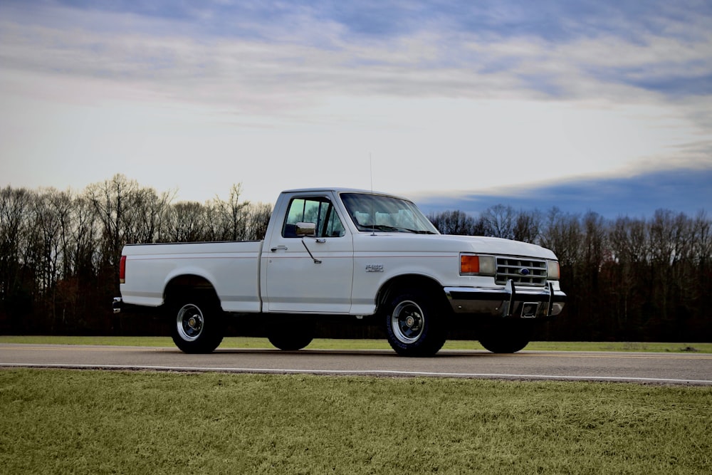 white crew cab pickup truck on green grass field under white clouds during daytime