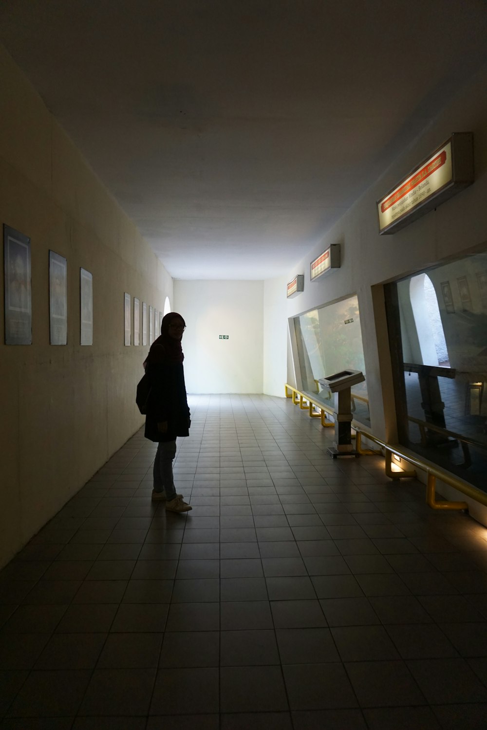 woman in black coat walking on hallway