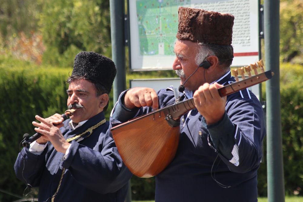 man in black jacket playing brown acoustic guitar