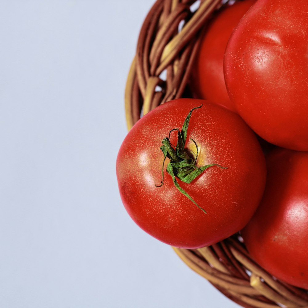 red tomato on brown woven basket