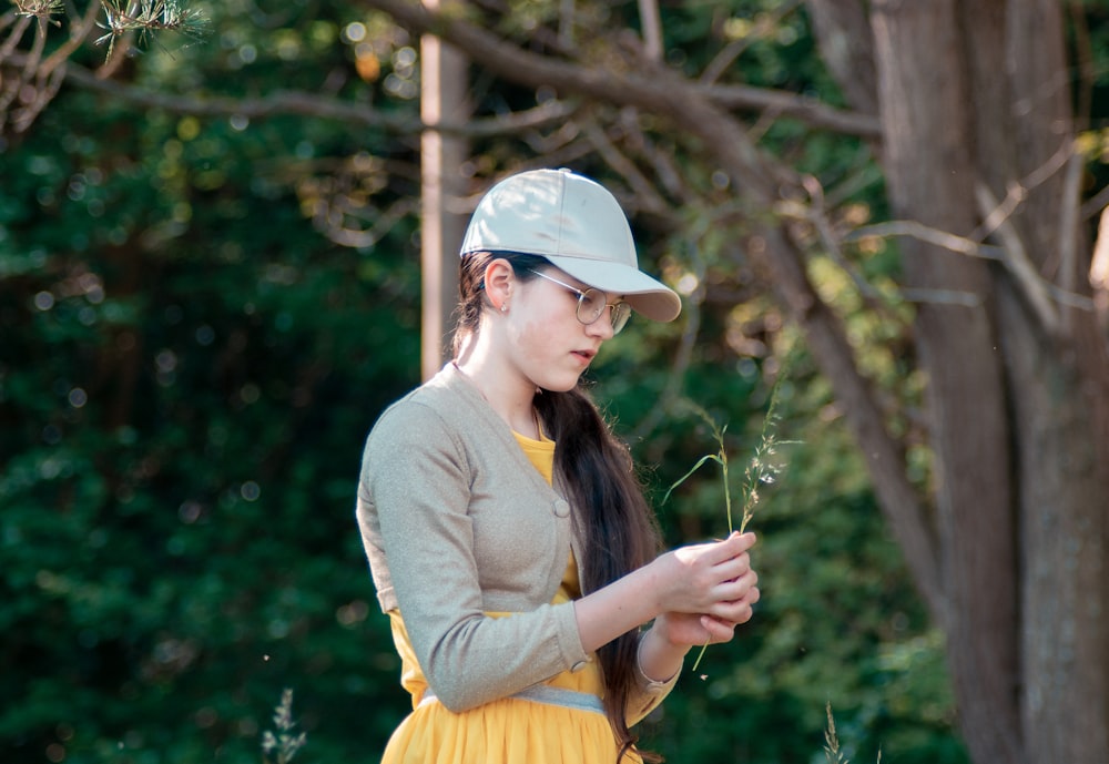 woman in white long sleeve shirt and yellow skirt holding green plant during daytime