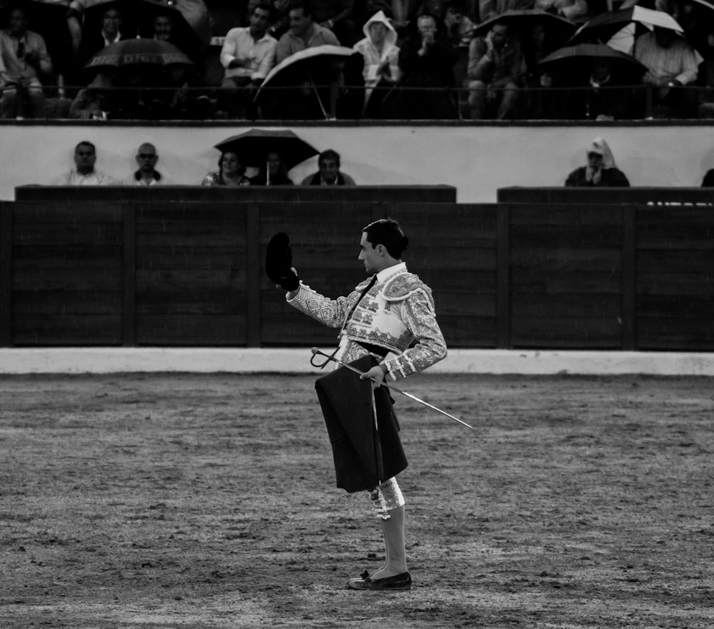 Foto en escala de grises de un hombre con camisa de jersey y pantalones cortos corriendo en el campo