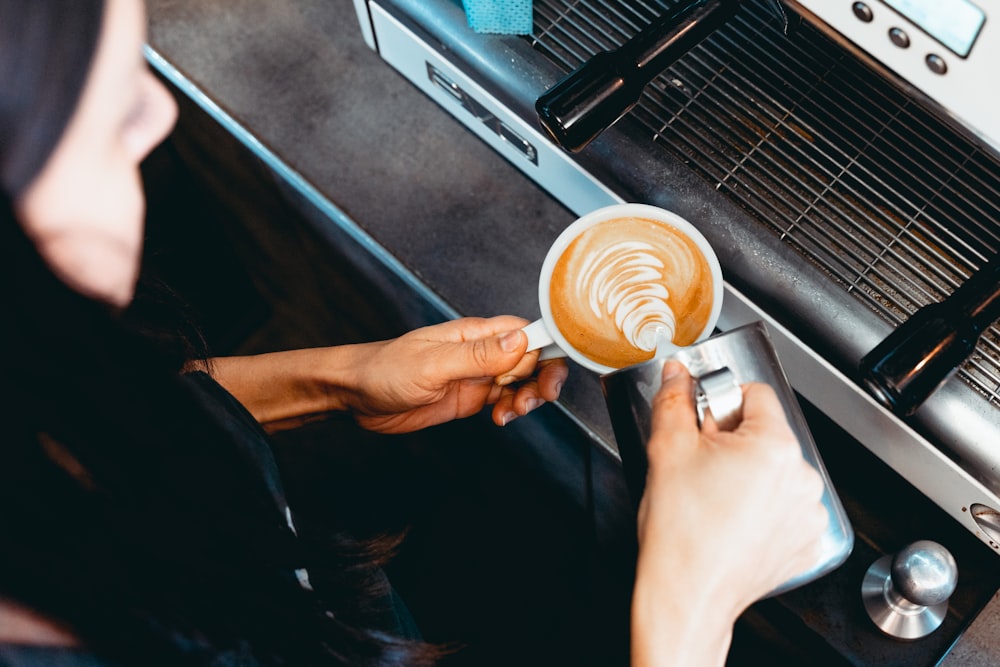 persona sosteniendo una taza de cerámica blanca