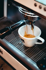 white ceramic cup on black and silver coffee maker