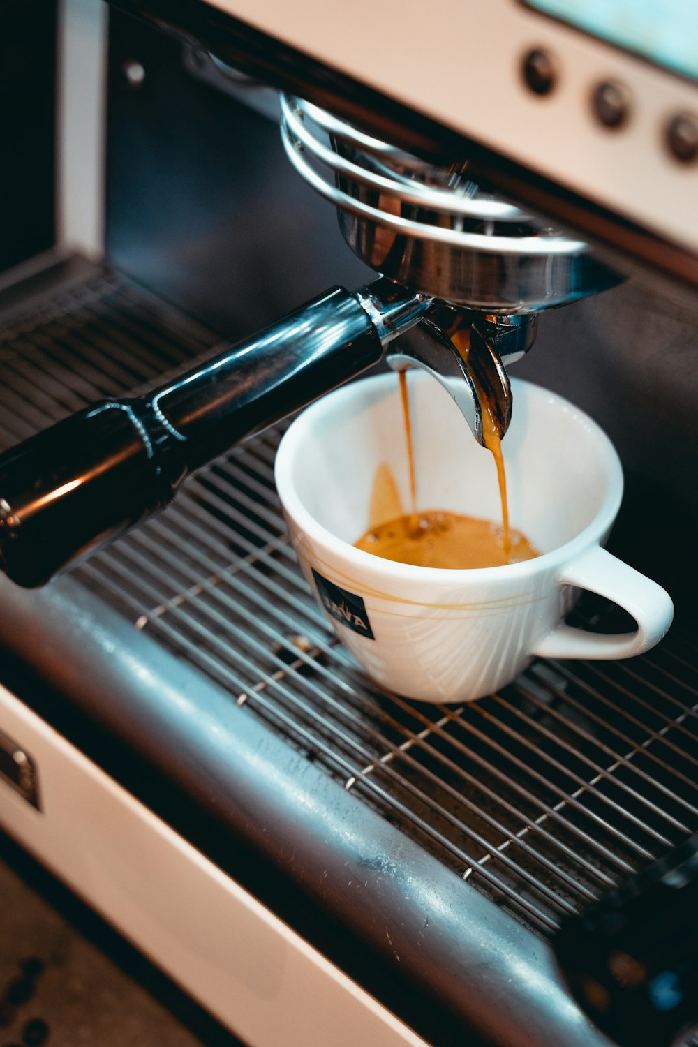 taza de cerámica blanca sobre cafetera negra y plateada