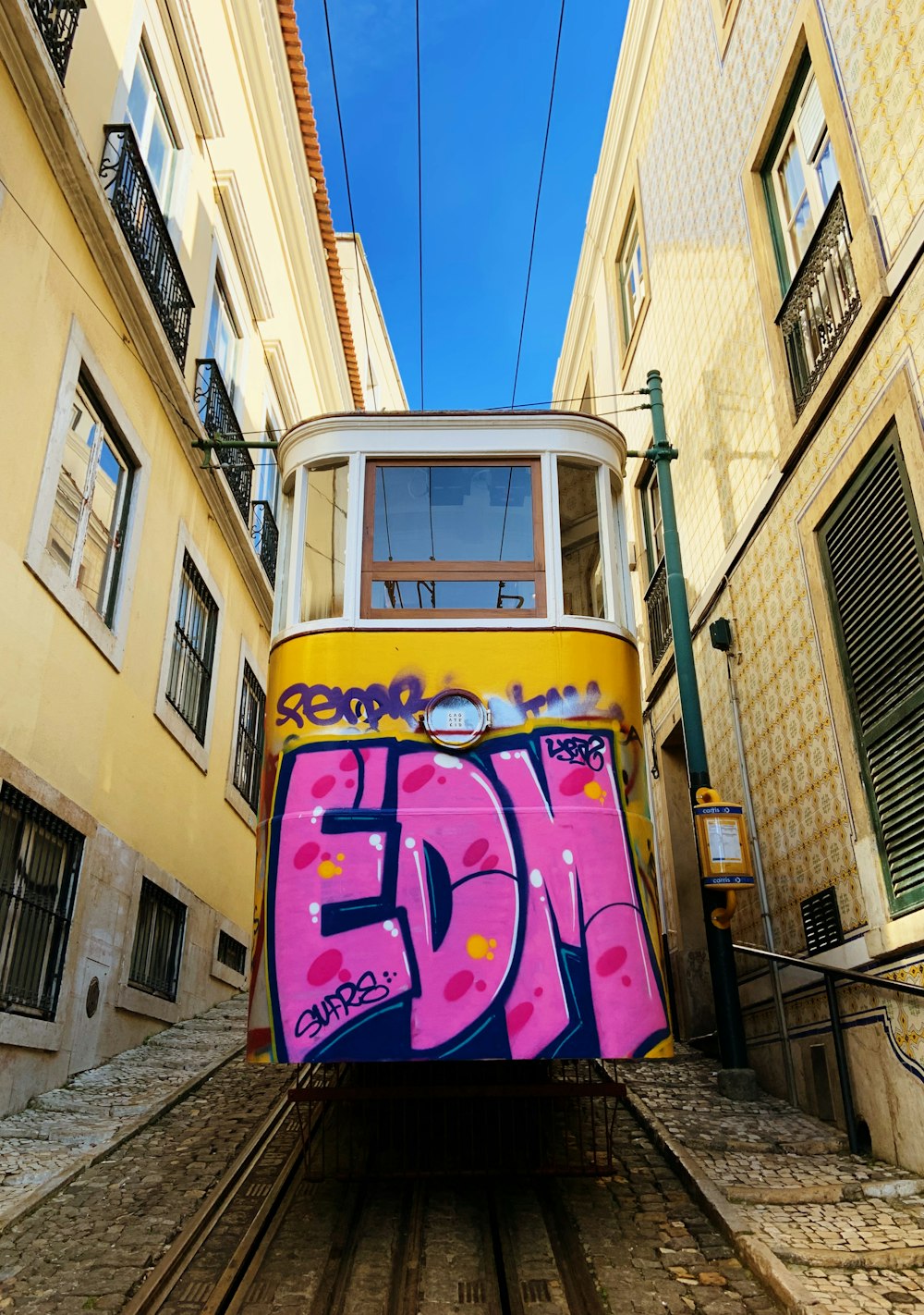 Graffiti di treni viola e gialli sul muro