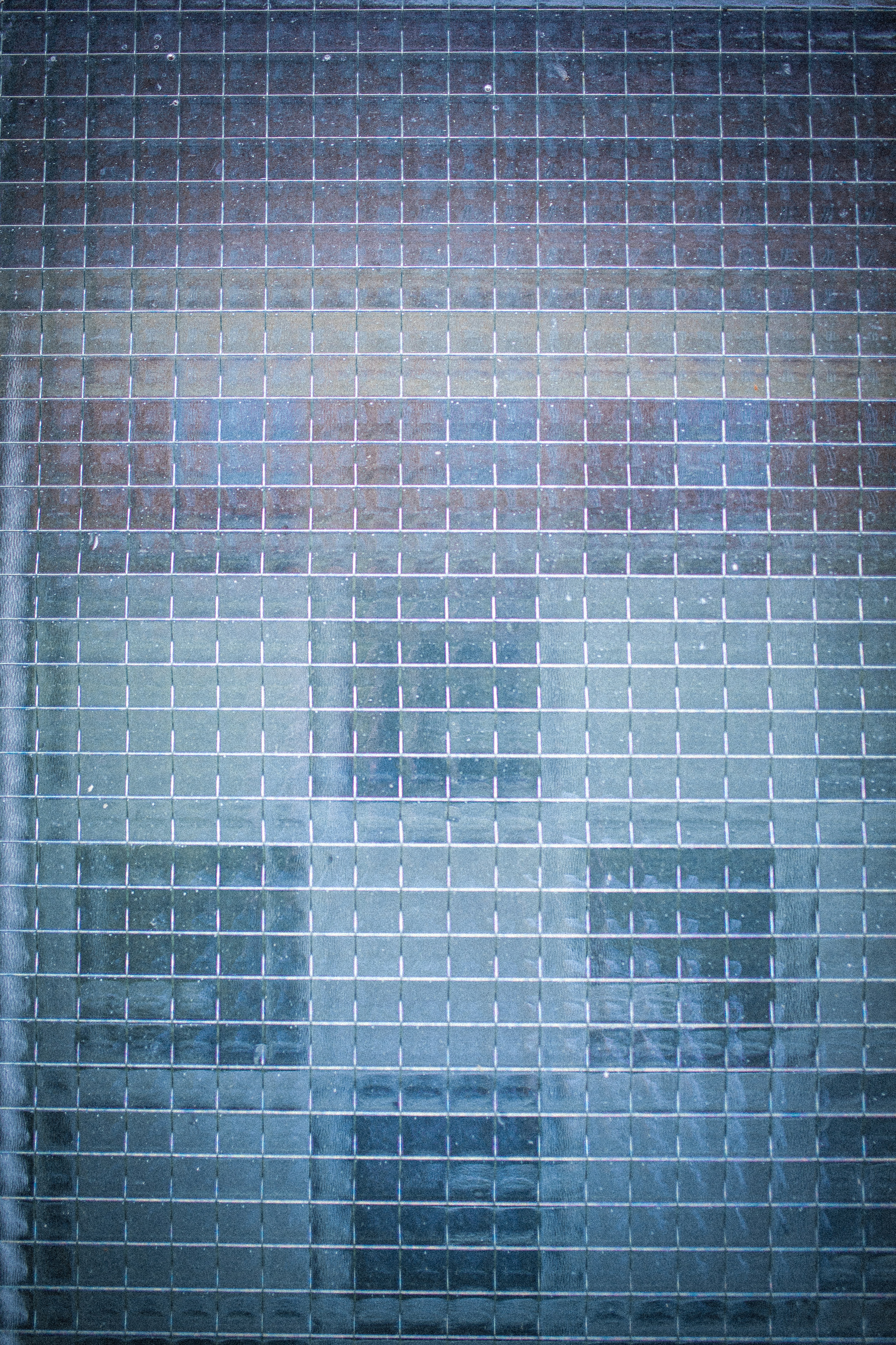 수직과 수평의 격자 무늬가 있는, 청회색을 띠는 질감이 있는 유리 표면의 클로즈업.