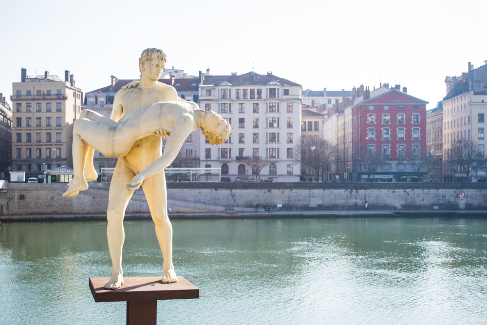 woman statue near body of water during daytime