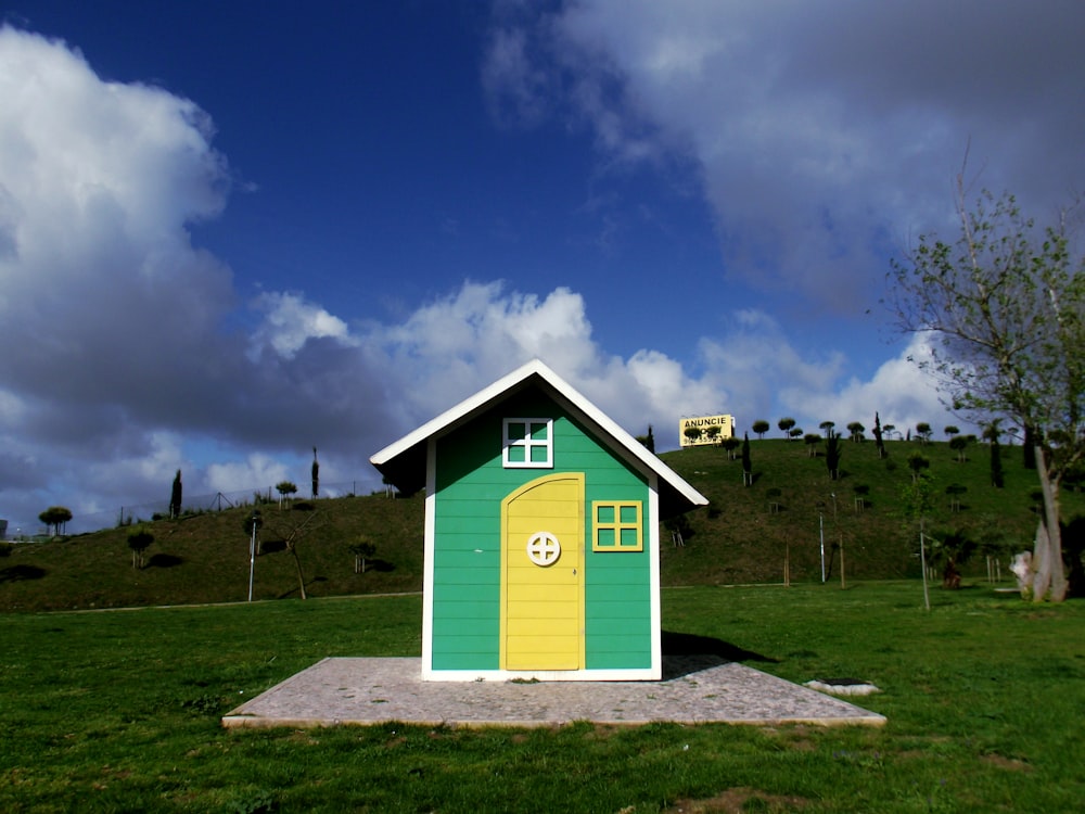 green and white wooden house on green grass field under blue sky during daytime