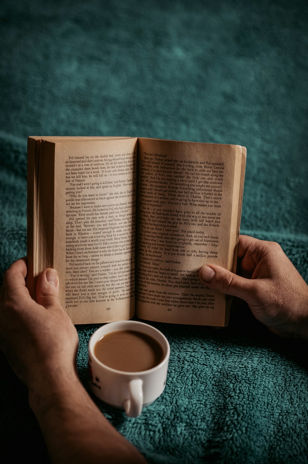 person reading book on green textile