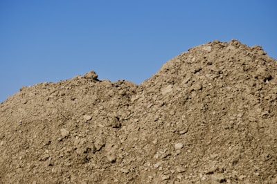 Iron ore piles with mountains in the background under a clear sky.