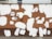 A brick wall with patches of white paint creating an irregular pattern against a predominantly brown surface. The wall features graffiti art, including a simple cartoonish figure and Russian text. The design and colors give a contrasted and eclectic feel to the urban setting.