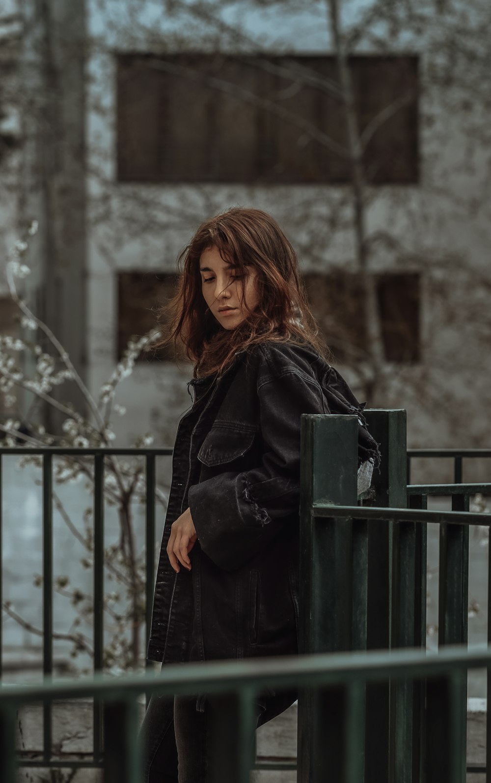 woman in black coat standing near black metal fence during daytime