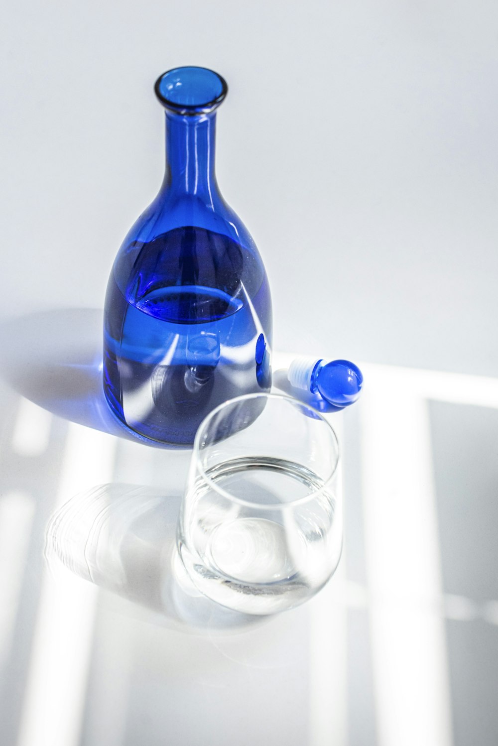 Botella de vidrio azul al lado de un vaso transparente