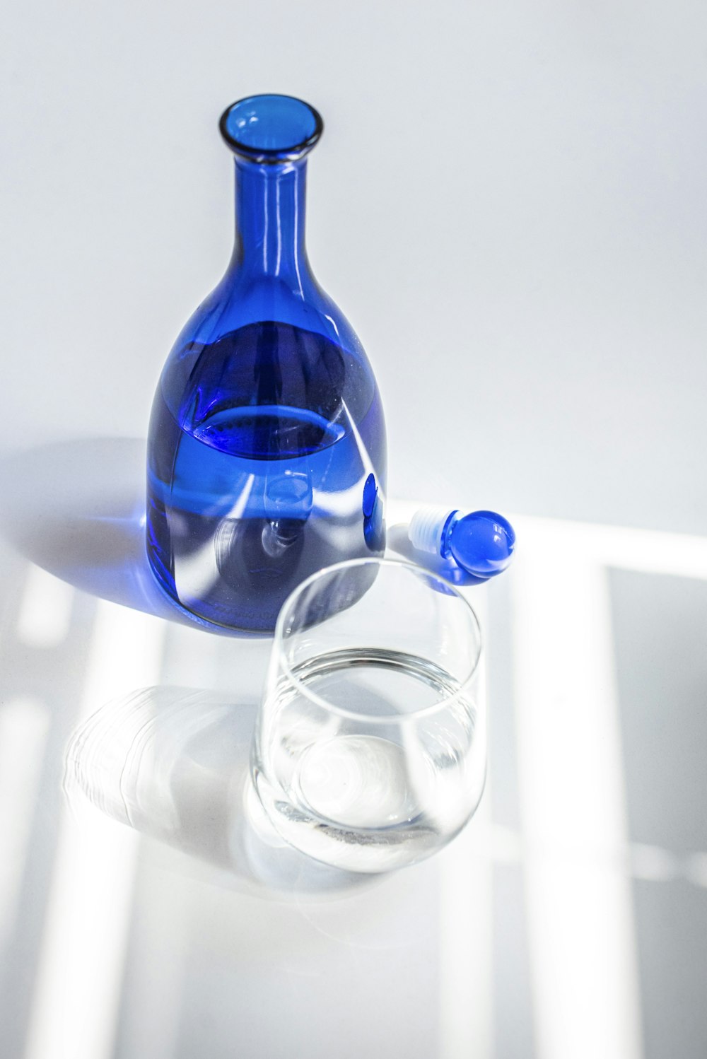 blue glass bottle beside clear drinking glass