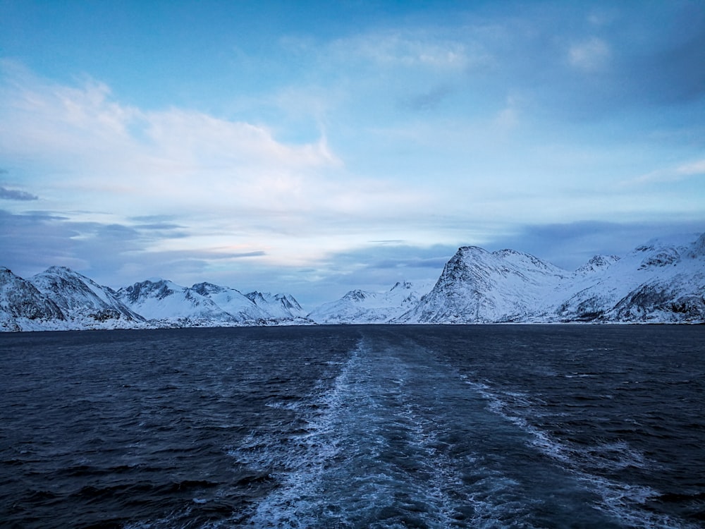 snow covered mountain near body of water during daytime