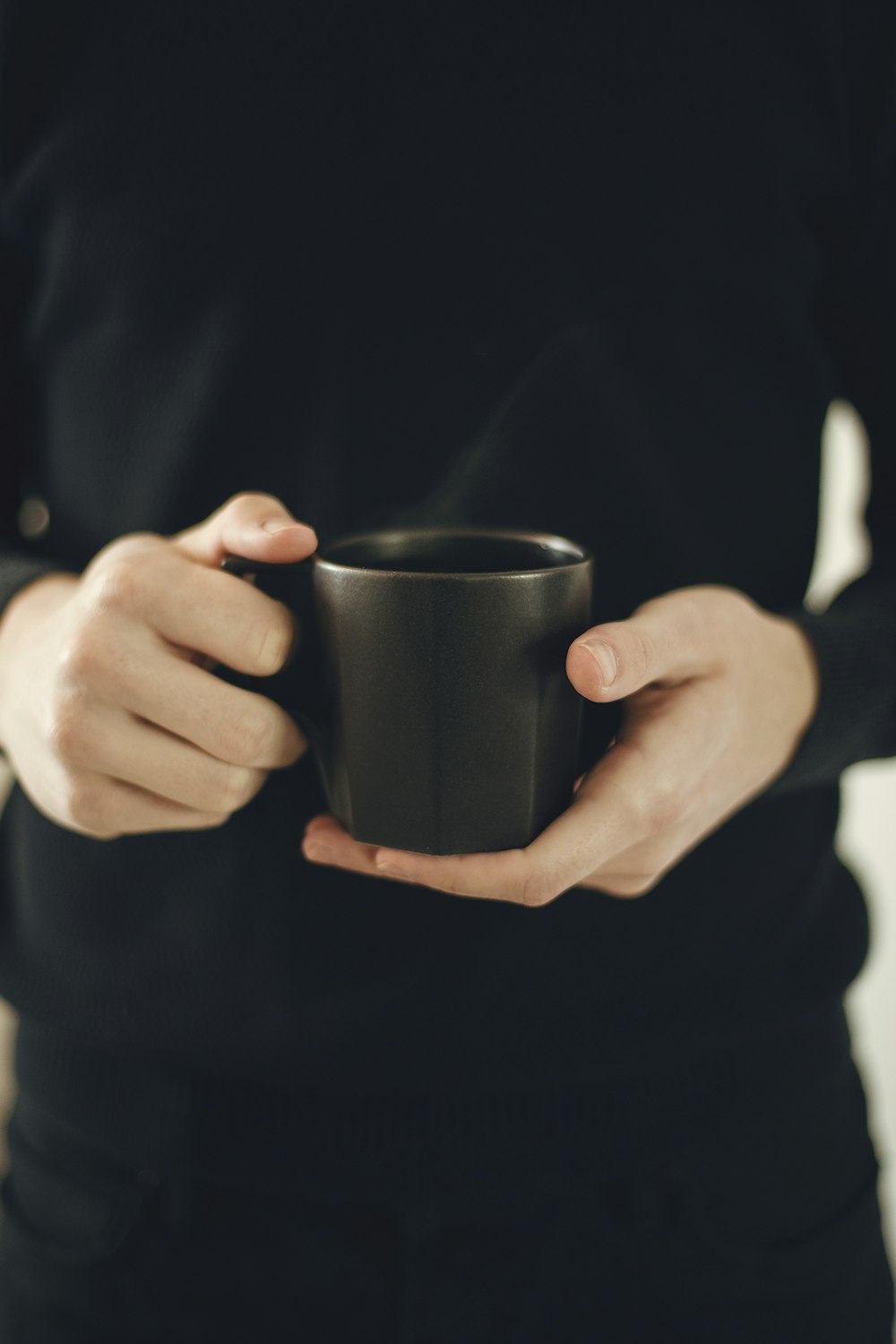 persona sosteniendo una taza de cerámica negra