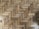 A close-up view of a wooden parquet floor with a herringbone pattern. The wood has various shades of brown and displays natural grain and knots, providing a rustic appearance.