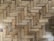 A close-up view of a wooden parquet floor with a herringbone pattern. The wood has various shades of brown and displays natural grain and knots, providing a rustic appearance.
