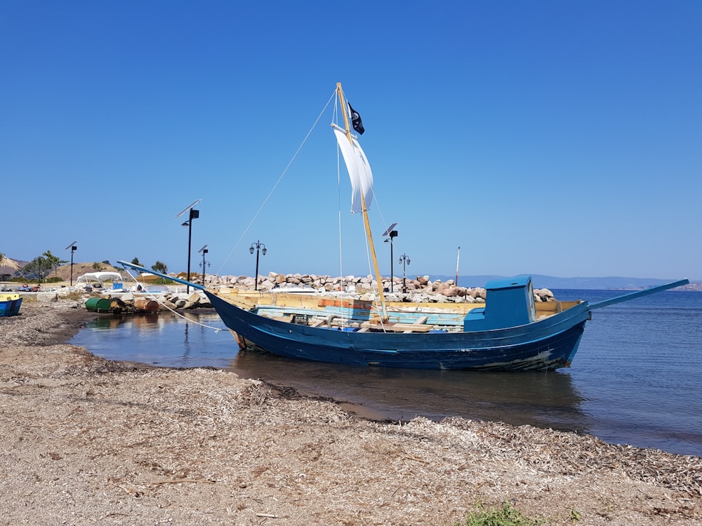 blue and white boat on beach during daytime