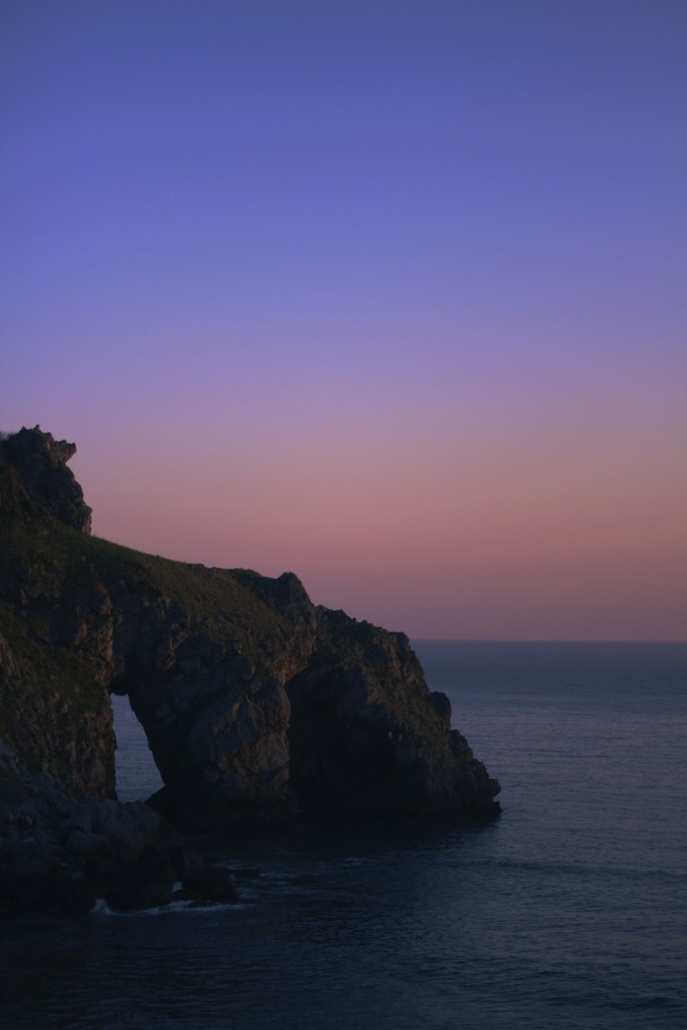 brown rock formation on sea during sunset