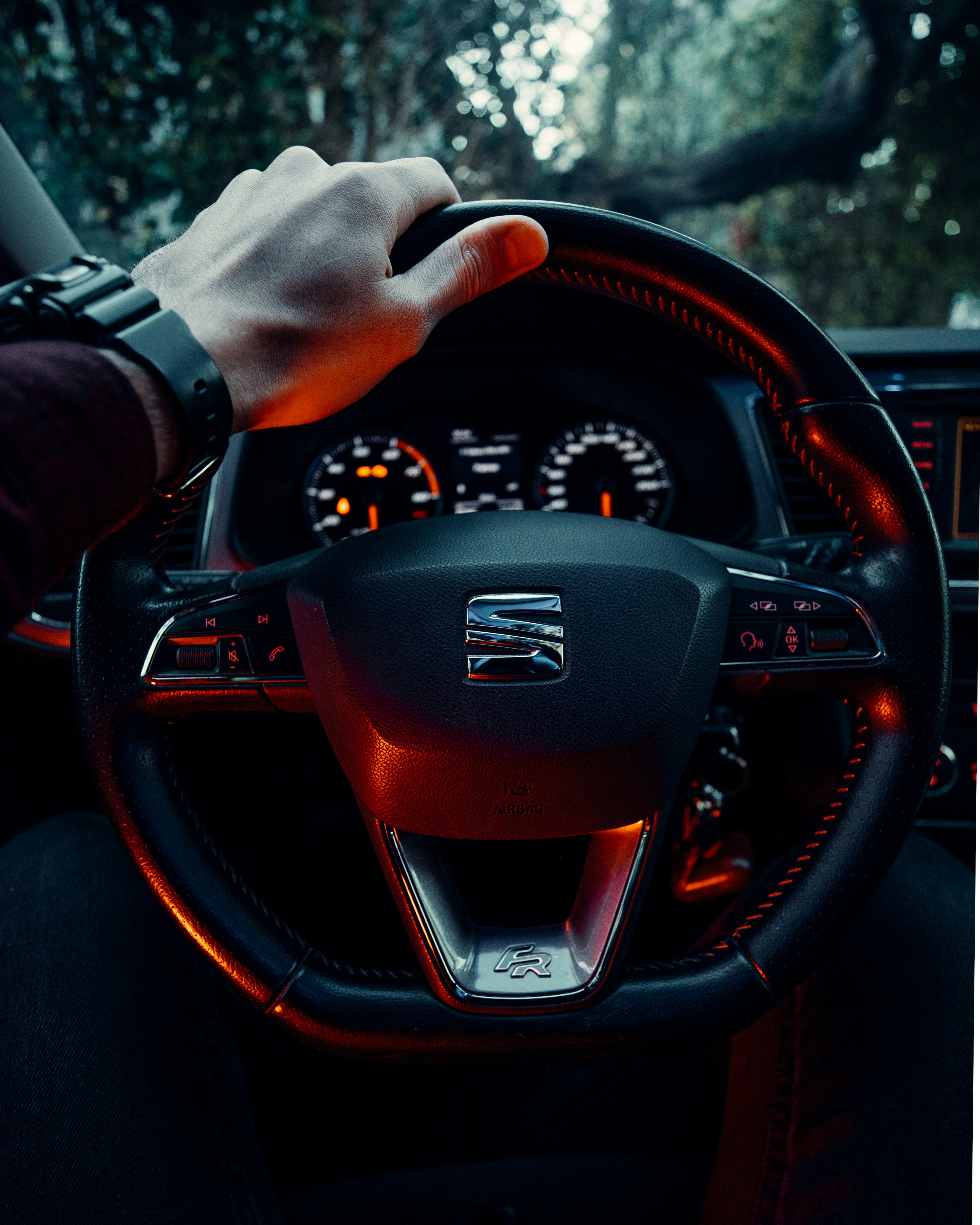 A driver grips the steering wheel while looking at the dashboard.